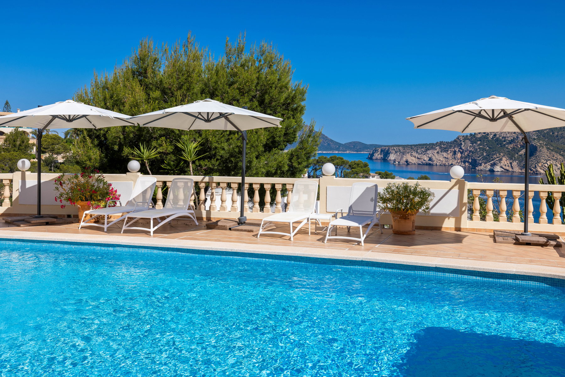 Solterrasse ved poolen med parasoller og liggestole